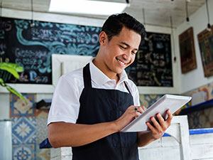 Young male cafe owner with tablet in his cozy and invitingly decorated cafe.